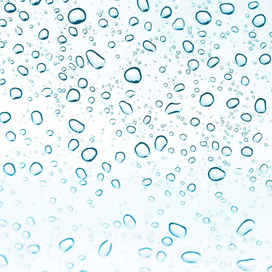 The image shows numerous water droplets on a clear surface, creating a pattern of various sizes of drops against a light blue background. The droplets are scattered evenly across the image, evoking a fresh and clean feeling, often associated with hydration and moisture.